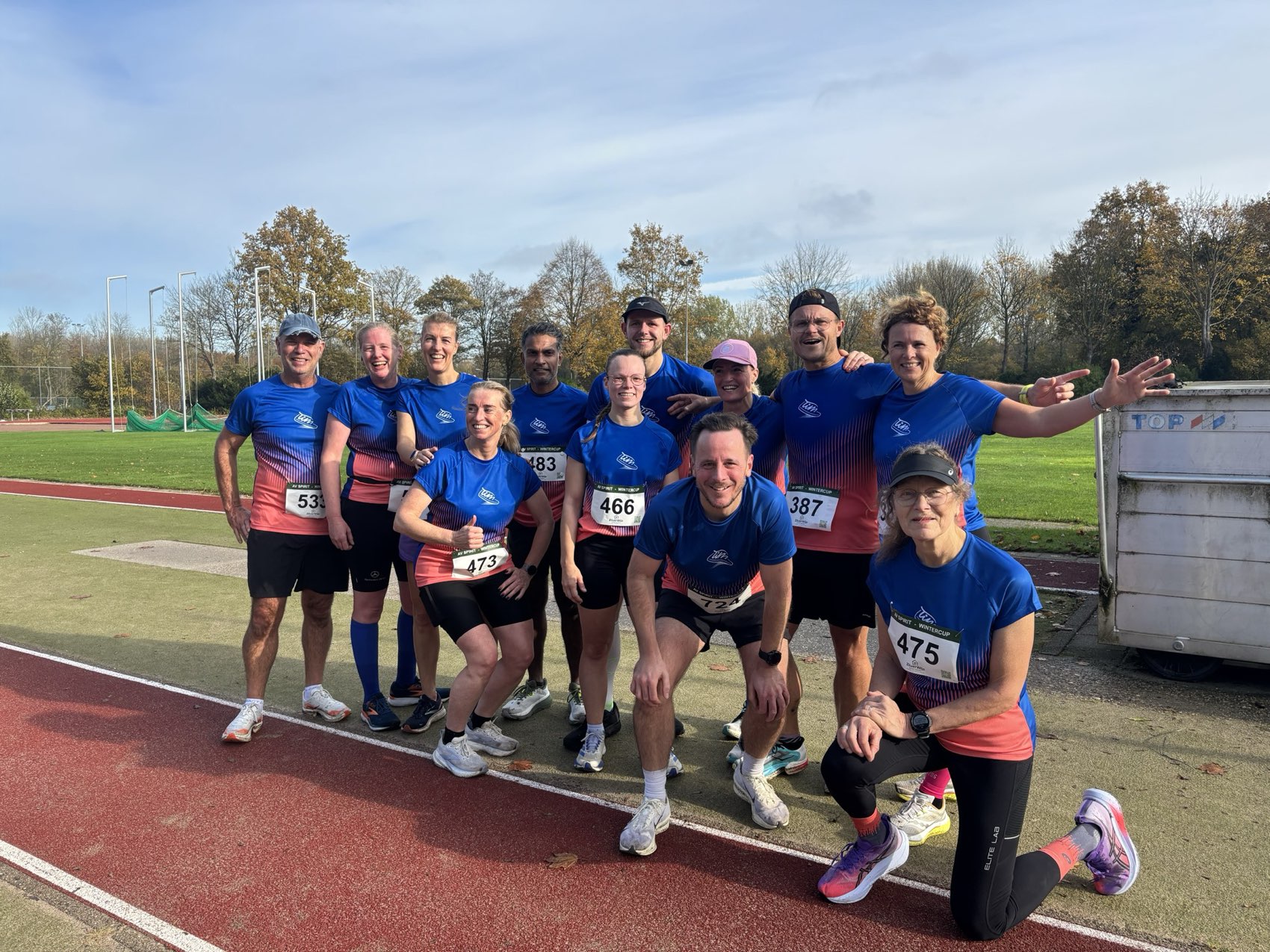 De leden van LelyRunners samen op de atletiekbaan, in clubtenue na een wedstrijd